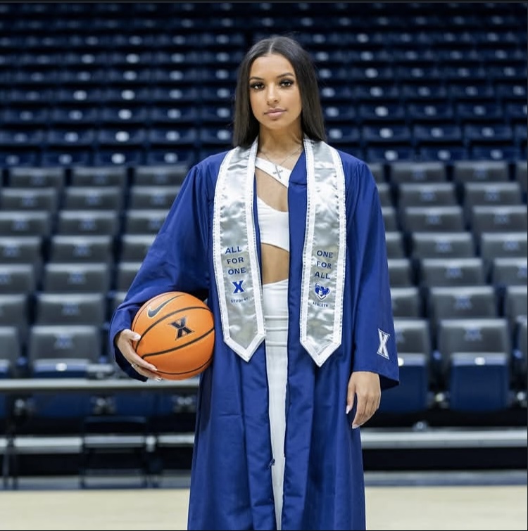 Shelby in her Xavier graduation gown, basketball in hand